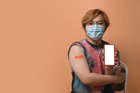 Asian man showing arm with plaster after getting vaccine.の写真素材