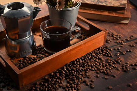 Digital tablet and roasted coffee beans on wooden table.