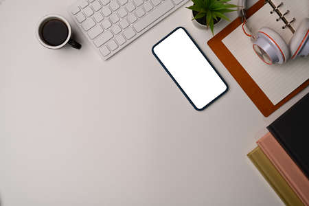 Woman holding mock up mobile phone with empty screen at her workspace.