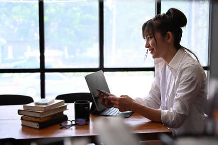 Peaceful young female student sitting in cafe and looking out of window.の写真素材