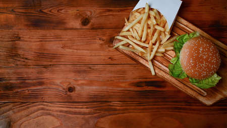 Homemade hamburger and fried potatoes on wooden tray.の写真素材