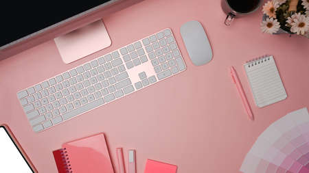 Designer workspace with computer, mobile phone and color swatches on pink background.の写真素材