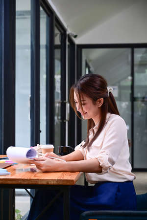 Happy young businesswoman holding coffee cup and talking on mobile phone.