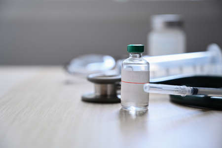 Syringe and bottle of vaccine on wooden table.の写真素材