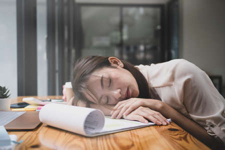 Tired young business woman sleeping at her office desk.の写真素材