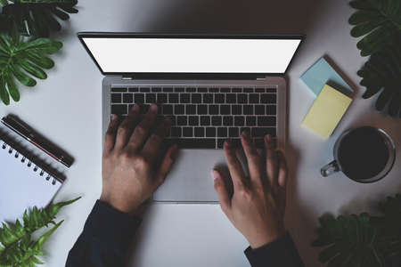 Businessman holding notepad and working with laptop.