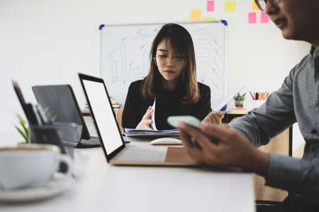 Business people discussing and analyzing financial graphs on whiteboard together in office.