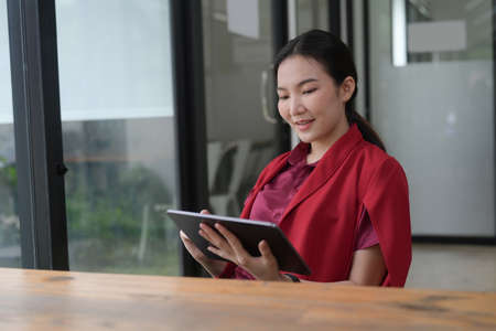 Businesswoman using mobile phone and working with laptop computer at office.