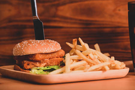 Delicious fish burger with fresh vegetables and cheese on wooden table.の写真素材