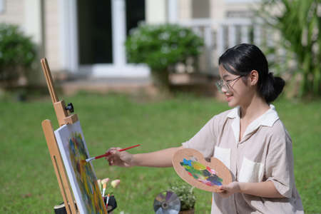 Happy girl holding painting brush and standing at the park.の写真素材