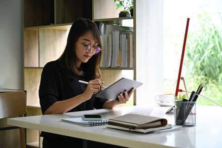 Businesswoman analyzing investment charts with computer in modern office.
