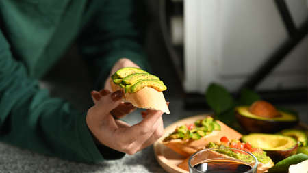 Woman holding plate with avocado toast and coffee cup.