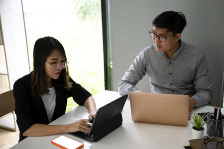 Two business colleagues analyzing graph on computer tablet together.