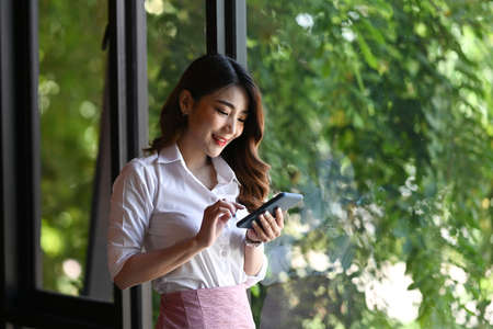 Asian businesswoman using smart phone in modern office.の写真素材