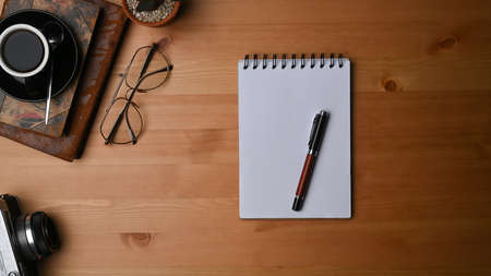 Photographer workspace with camera, laptop computer and coffee cup on wooden desk.の写真素材