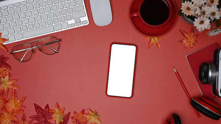 Mock up mobile phone, coffee cup, camera and maple leaves on red background.の写真素材