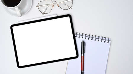Flat lay, digital tablet with blank screen and notebook on white desk.の写真素材