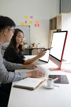 Two business people discussing business data on computer together at office.の写真素材