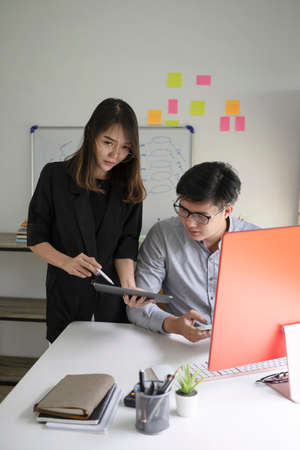 Two business people discussing business data on computer together at office.の写真素材