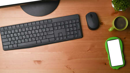 Mobile phone, coffee cup and houseplant on office desk.の写真素材