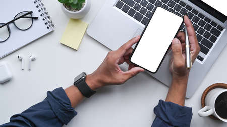 Above view businessman using smart phone at office desk.
