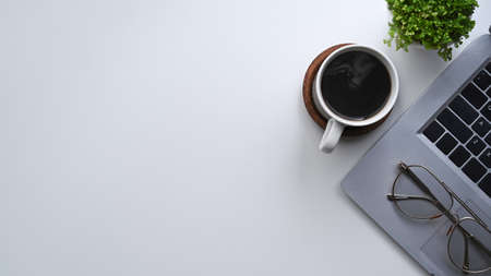 Above view computer laptop, coffee cup and notebook on white desk.の写真素材