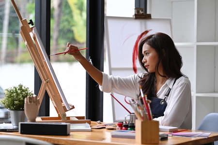Pretty female artist painting with watercolors in the workshop.