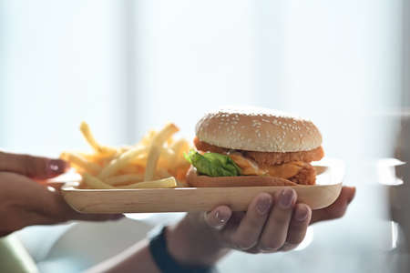 Woman holding homemade delicious crispy fish burger.の写真素材