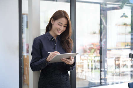 Attractive young woman sitting in modern office and smiling to camera.
