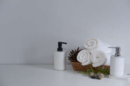 Soap bottles and wooden tray of towels on white table. Beauty spa treatment and relax concept.