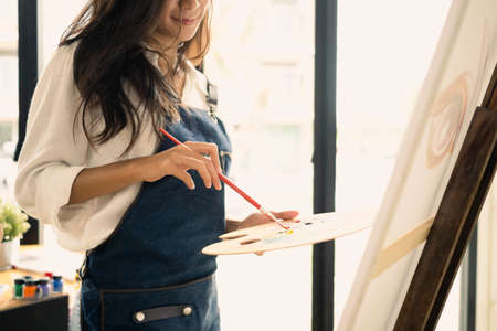 Pretty female artist painting with watercolors in the workshop.