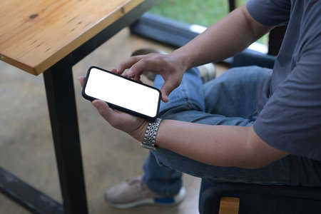 Cropped shot man sitting at outdoor and using smart phone.の写真素材