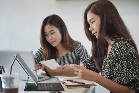 Two young female designer working together on project in creative office.