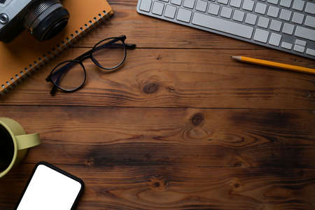 Top view simple workspace with computer, wireless keyboard, notebook and coffee cup on wooden desk.の写真素材