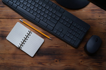 Above view empty notepad, pencil and keyboard on wooden table.の写真素材