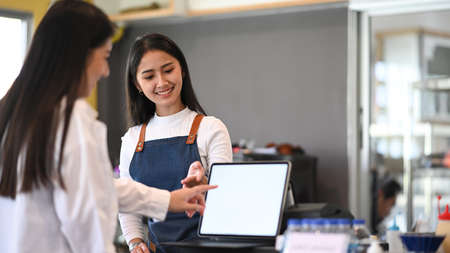 Friendly female waitress recommending  menu to her customers.の写真素材
