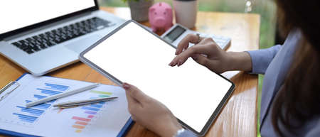 Close up view female accountant using digital tablet while sitting at her office desk.