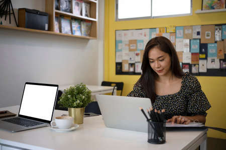 Young female designer working with laptop computer in creative office.の写真素材