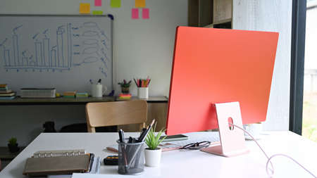 Computer, plant and office supplies on white office desk.