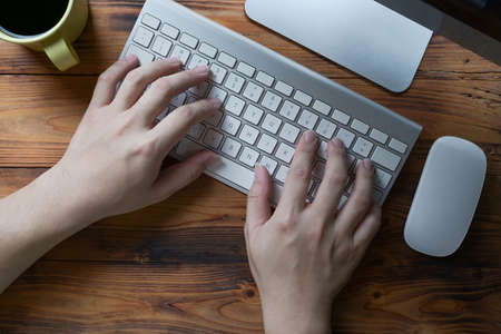 Young man hands typing on wireless keyboard.