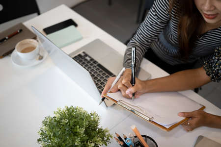 Young woman pointing on document and explaining information for her colleague.の写真素材