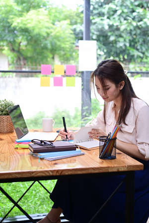 Smiling young female sitting coffee shop and using smart phone.の写真素材