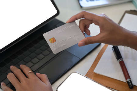 Close up female using computer tablet and holding credit card for banking online.の写真素材