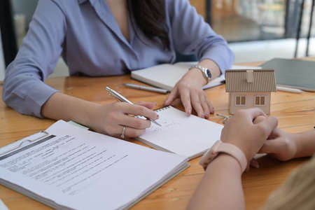 Female estate agent explaining contract details for her customer. Real estate and mortgage investment.の写真素材