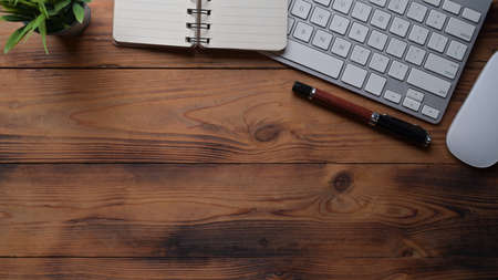 Top view notebooks, coffee cup, keyboard and houseplant on wooden table.の写真素材