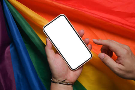 Man holding mock up smart phone over LGBT rainbow flag.の写真素材