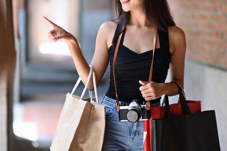 Beautiful woman holding shopping bags while walking down the city street.の写真素材