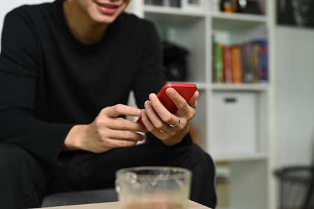 Overhead shot man sitting on couch and using smart phone.