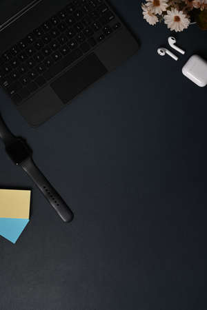 Top view smart watch, laptop computer and earphones on black leather.