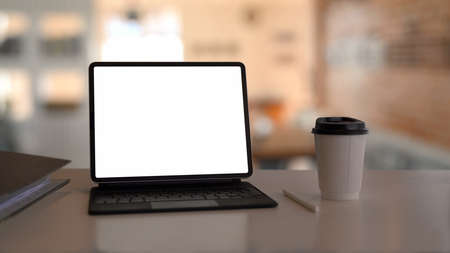 Computer tablet with blank display and coffee cup on white table.の写真素材